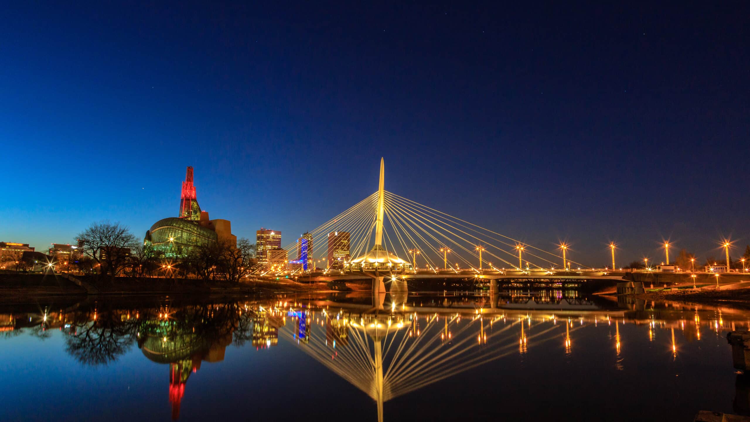 Night view of illuminated bridge over calm water.