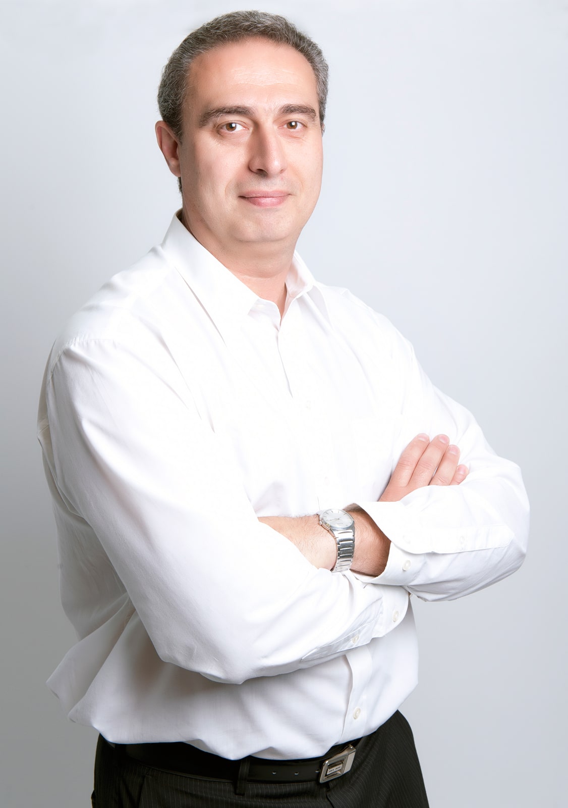 Man in white shirt, arms crossed, professional pose.