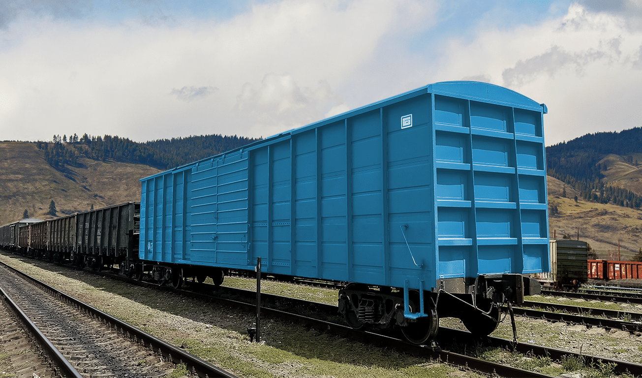 Blue freight train car on tracks, rural landscape background