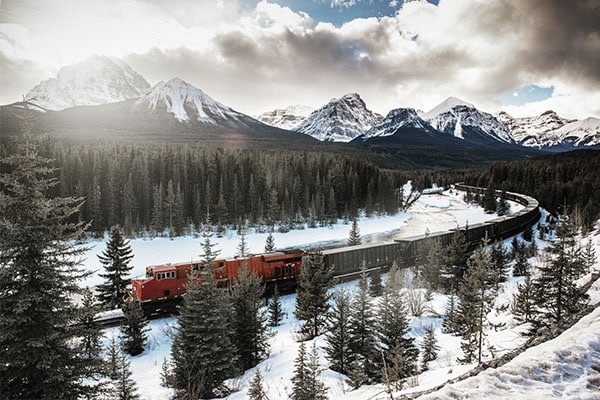 Train traveling through snowy mountain landscape.