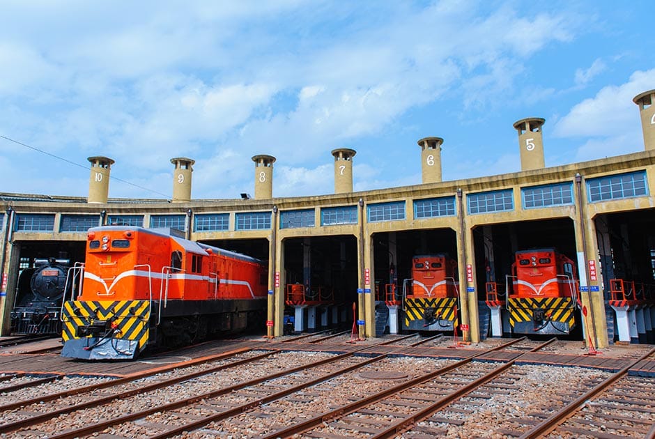 Roundhouse with orange trains parked inside.