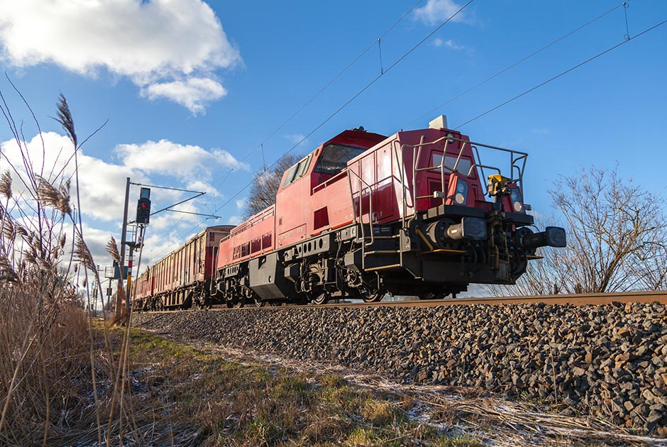 Red freight train on sunny day railway track.